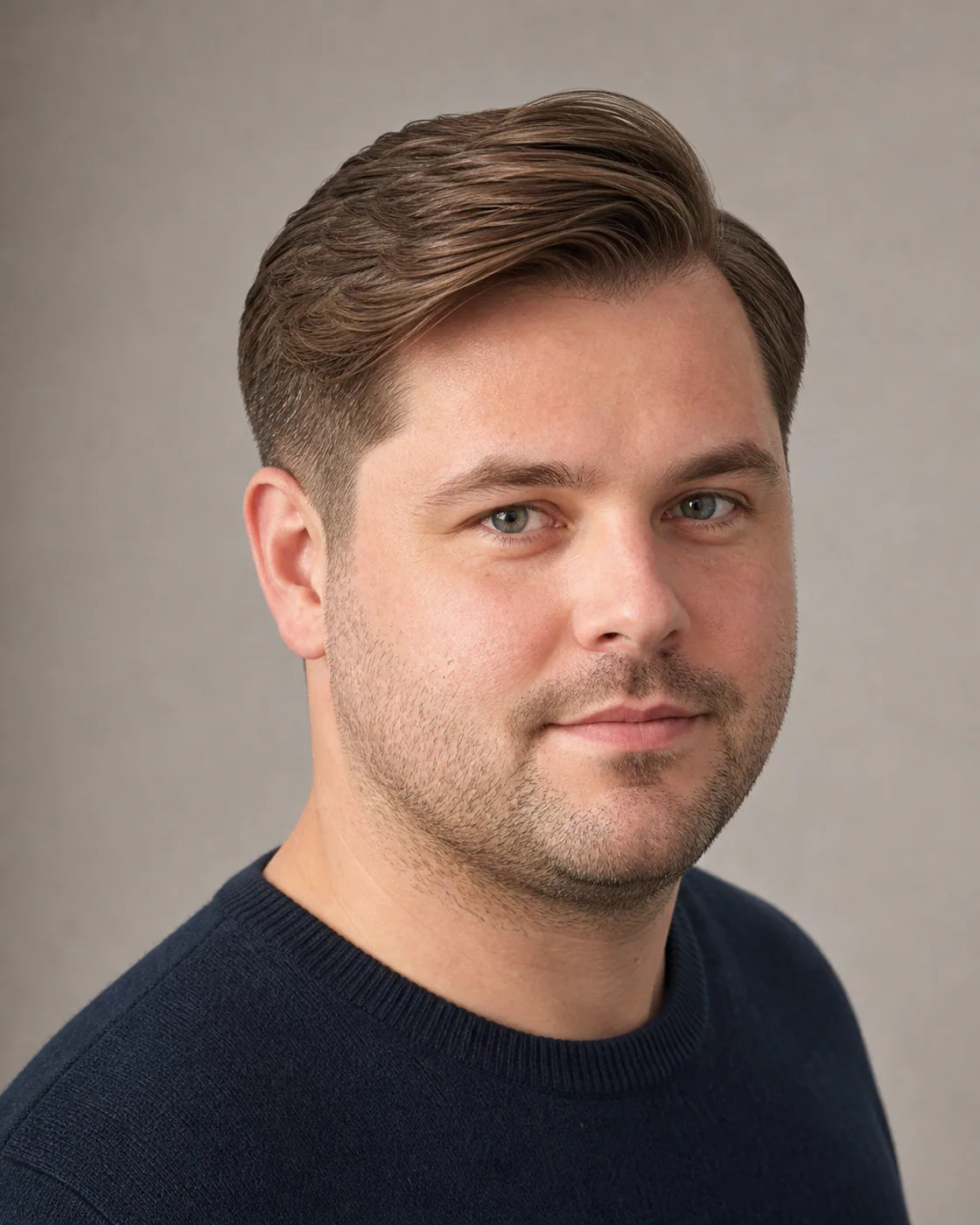 A man with a round face wearing a classic side part and low taper