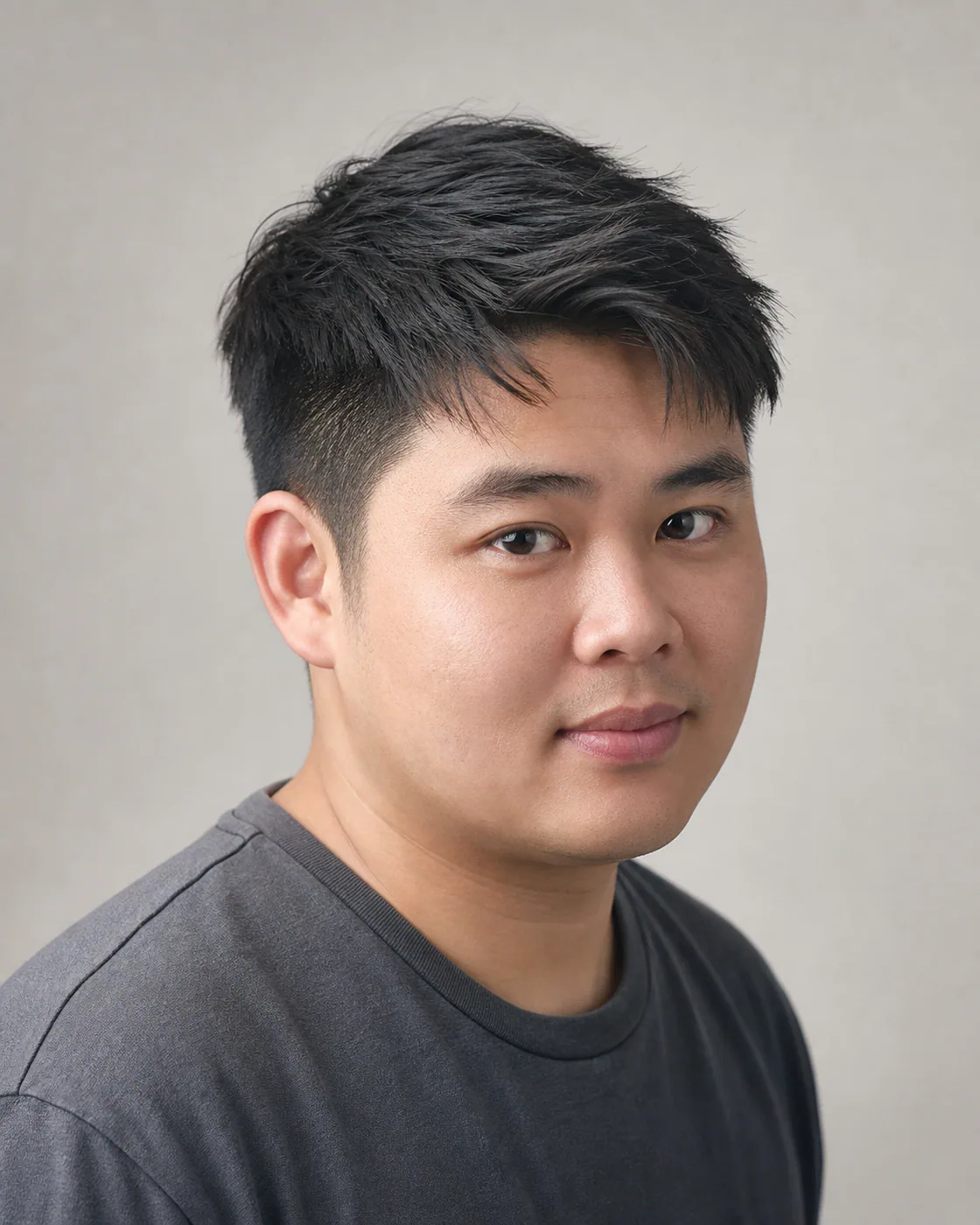 A man with a round face wearing a side-swept textured crop with a light diagonal fringe
