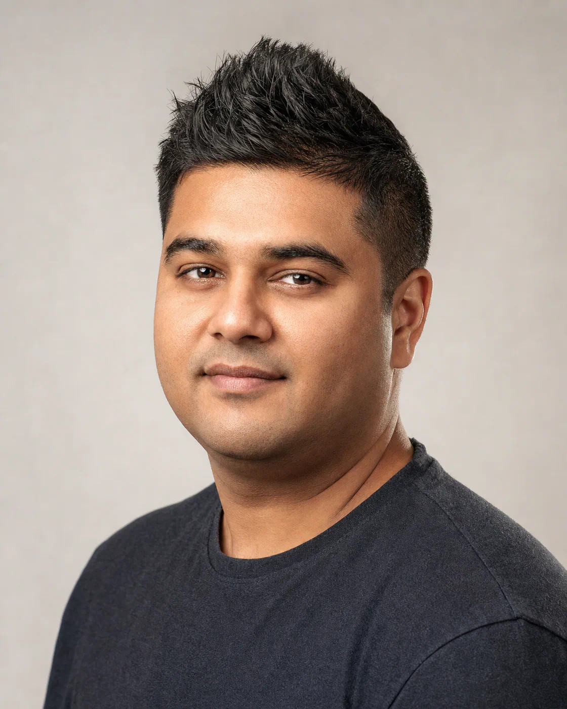 A man with a round face wearing a subtle textured faux hawk