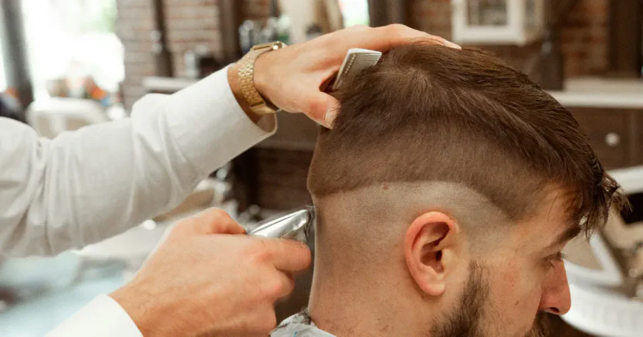 A barber creating a faded haircut for a man